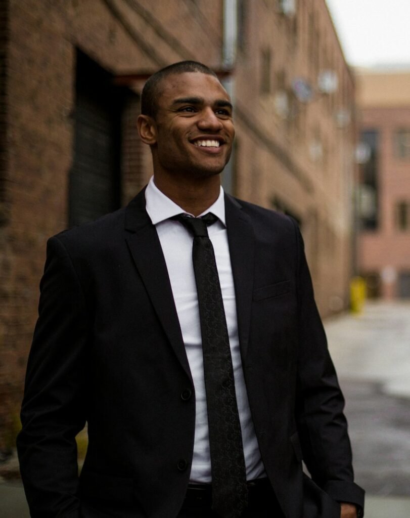 smiling man standing between brown concrete buildings at daytime